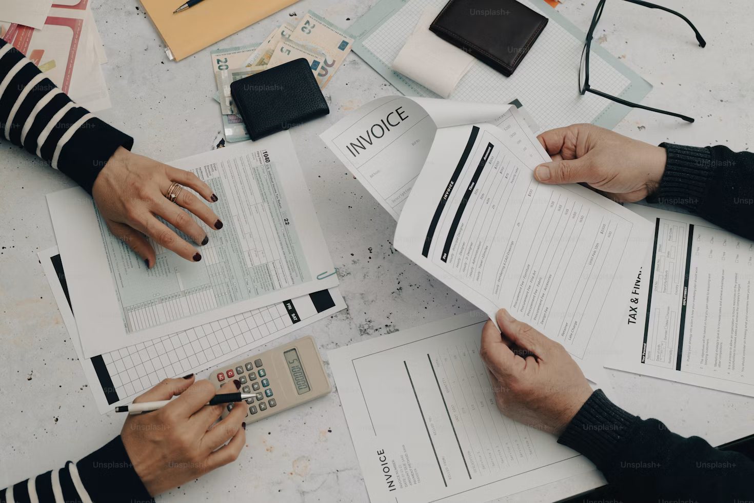 Two advisors reviewing invoices and tax forms with a calculator